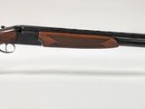 un gros plan d'un fusil posé sur un socle transparent, sur une surface blanche