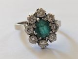gros plan d'une bague avec une pierre verte entourée de diamants blancs