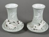 une paire de vases blancs ornés de personnages, posés sur une table