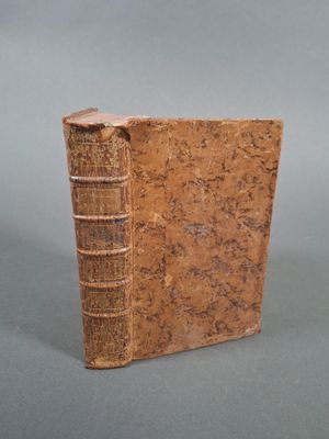 un vieux livre posé sur une table à côté d'un fond gris