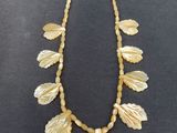 an image of a necklace with shells and leaves on it