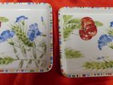 two plates with flowers on them sitting on a red cloth