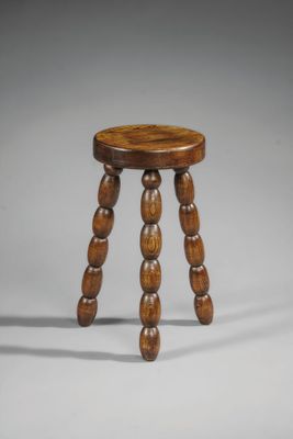 un petit tabouret en bois aux pieds tournés, sur fond gris