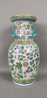 un vase blanc orné de motifs colorés sur un fond gris