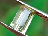 un diamant vert maintenu par une pince à épiler