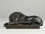 a bronze statue of a lion on a wooden base