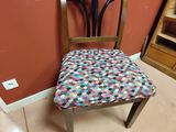 une chaise en bois avec une assise multicolore dans une pièce