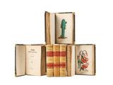 several old books are stacked on top of each other on a white surface