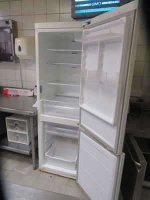 an open refrigerator in a kitchen with a tv in the background