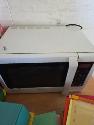 un micro-ondes blanc posé sur une pile de chemises colorées