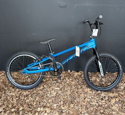 Le vélo bleu est appuyé contre le mur, devant un mur noir.