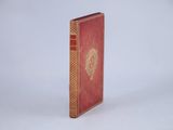 a red book with gold trim sitting on a white surface