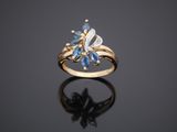a gold ring with blue sapphires and diamonds on a black surface