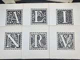 four black and white cards with the letters a, b, c, d, e, n, v