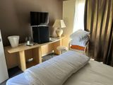 a bed with a white comforter and a television in the corner