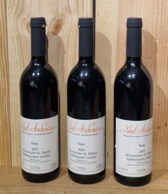 three bottles of red wine sit on a shelf in front of a wooden wall