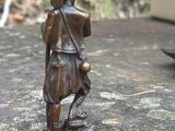 une statue en bronze représentant un homme avec un chien, assis sur un rocher