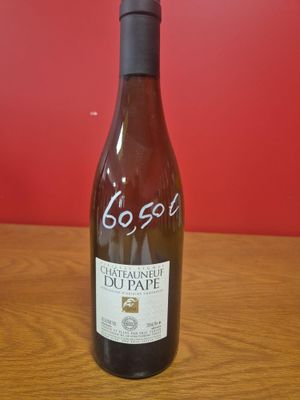 La bouteille de vin est posée sur la table, devant un mur rouge.