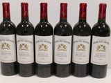 six bottles of red wine are lined up on a white surface