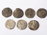 six pièces de monnaie romaines antiques posées sur une surface blanche, sur fond blanc