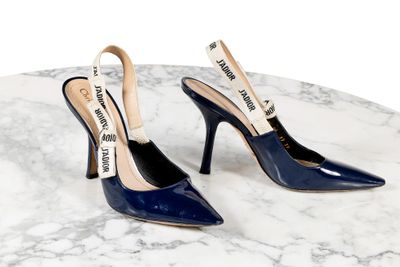 Les escarpins bleus sont posés sur une table en marbre, sur fond blanc.