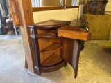 a corner cabinet with a drawer in the middle of it