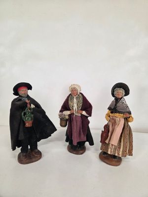 trois figurines représentant des personnages vêtus de costumes médiévaux et coiffés de chapeaux