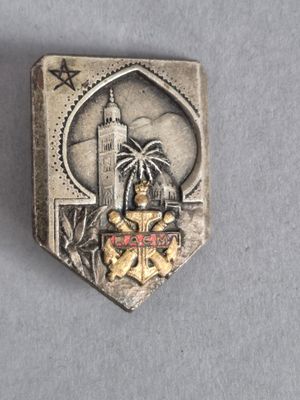 deux insignes en argent et en or sur lesquels figurent un phare et un palmier