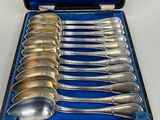 six silver spoons in a blue case on a table