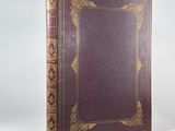 a brown book with gold trim sitting on top of a white surface
