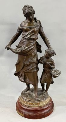 a bronze statue of a woman holding a child on top of a wooden base