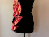 Le mannequin porte une robe rose et noire.