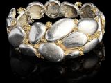 un gros plan d'un bracelet en argent et en or posé sur une surface noire