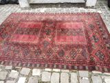 an old rug on a cobblestone street with a bench in the background