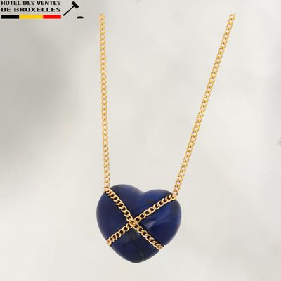 un collier en forme de cœur bleu avec une chaîne dorée sur fond blanc