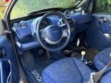 the interior of a small car with blue seats and a steering wheel