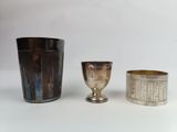 trois tasses en argent posées l'une à côté de l'autre sur une table