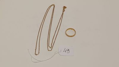deux bagues en or et un collier posés sur une surface blanche