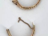a pair of gold earrings on a white surface