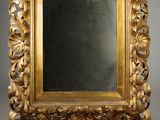 un miroir orné d'un cadre doré sur fond gris