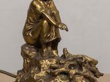 statue représentant une femme assise sur un rocher à côté d'un chien