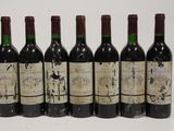 six bottles of wine are lined up in a row on a white surface