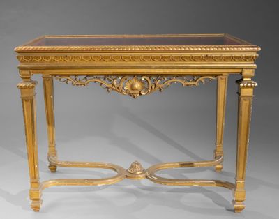 une console ancienne avec un plateau en verre et des décorations à la feuille d'or