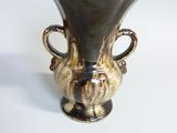 a black and gold vase sitting on a white surface