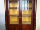 a large wooden cabinet with glass doors and a clock on top