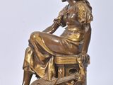 bronze statue of a woman sitting on a box with a guitar