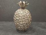 un vase argenté en forme d'ananas posé sur une table noire