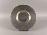 a silver plate on a stand on a white surface