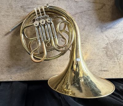 a close up of a brass french horn on a black cloth