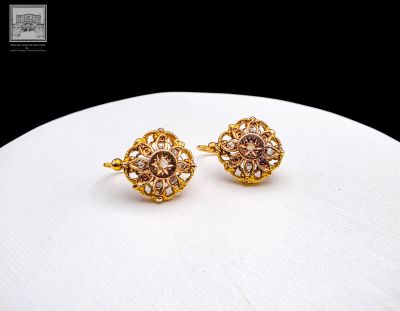 gold plated earrings with pink stones on a white surface